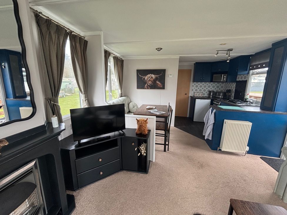 A living room with a television and dining area at No 38 Heilan Hoose at Three Lochs Newton Stewart