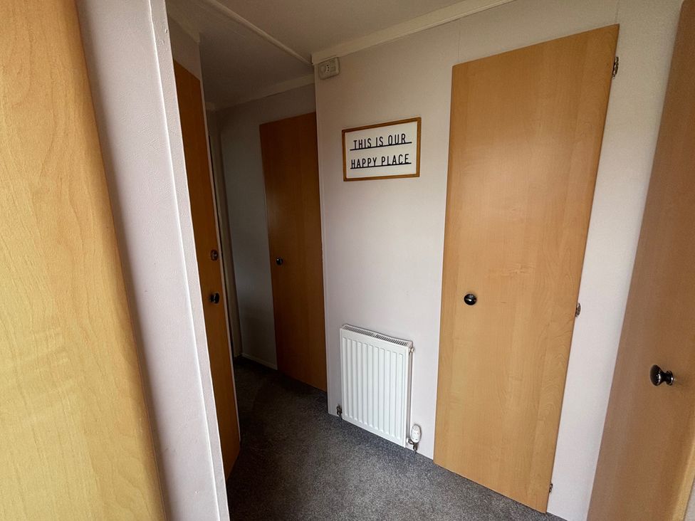 A hallway with multiple doors and a sign at No 38 Heilan Hoose at Three Lochs Newton Stewart