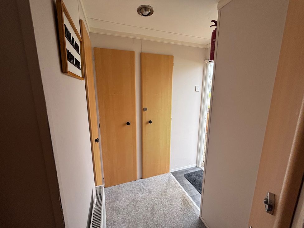 A hallway with doors and a carpet at No 38 Heilan Hoose at Three Lochs Newton Stewart