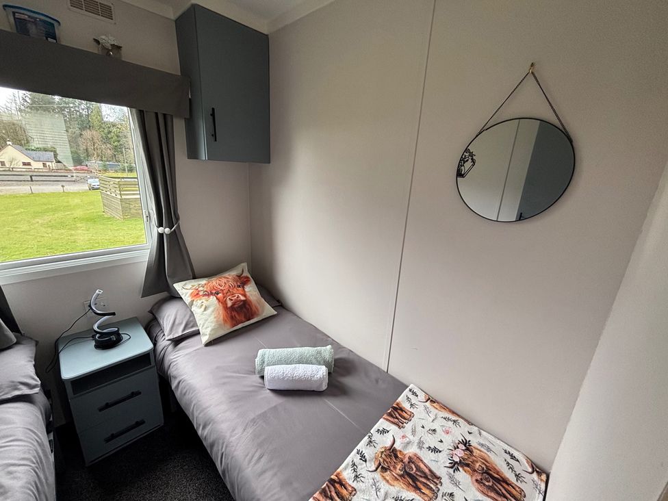 A bedroom with beds, a mirror, and a bedside table at No 38 Heilan Hoose at Three Lochs Newton Stewart