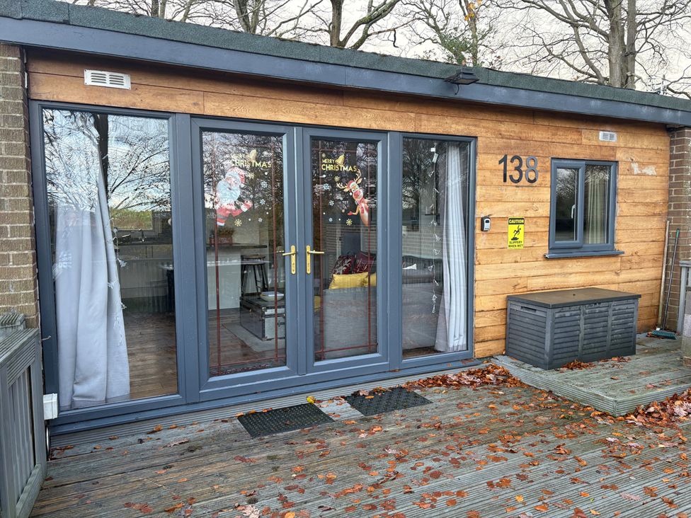 An outdoor view of a lodge with glass doors and wooden exterior at Pet Friendly 2-Bed Lodge, Sleeps 5, Pool & Parking, Caernarfon
