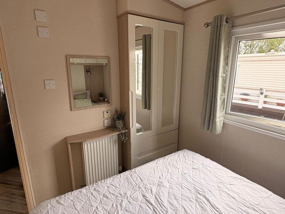 A bedroom with a mirror and wardrobe at Caravan - Sleeps 8 - Parking Northampton