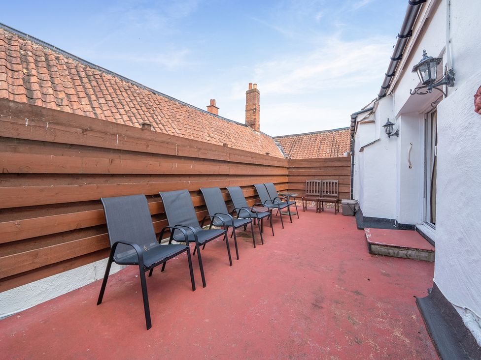 A terrace with chairs and a wooden bench at House in historic village - Sleeps 6, Dunster