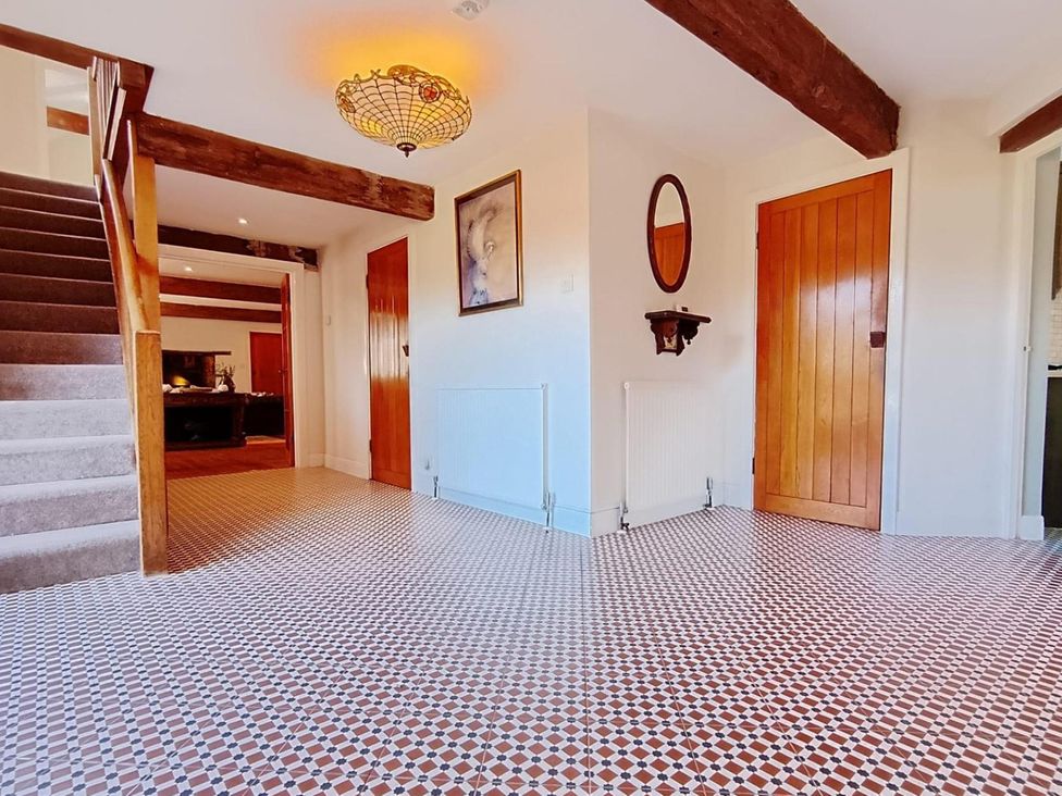 A hallway with a staircase and wooden door at Sharvels Oast House - Pool, Tennis, Luxury Home, Peasmarsh