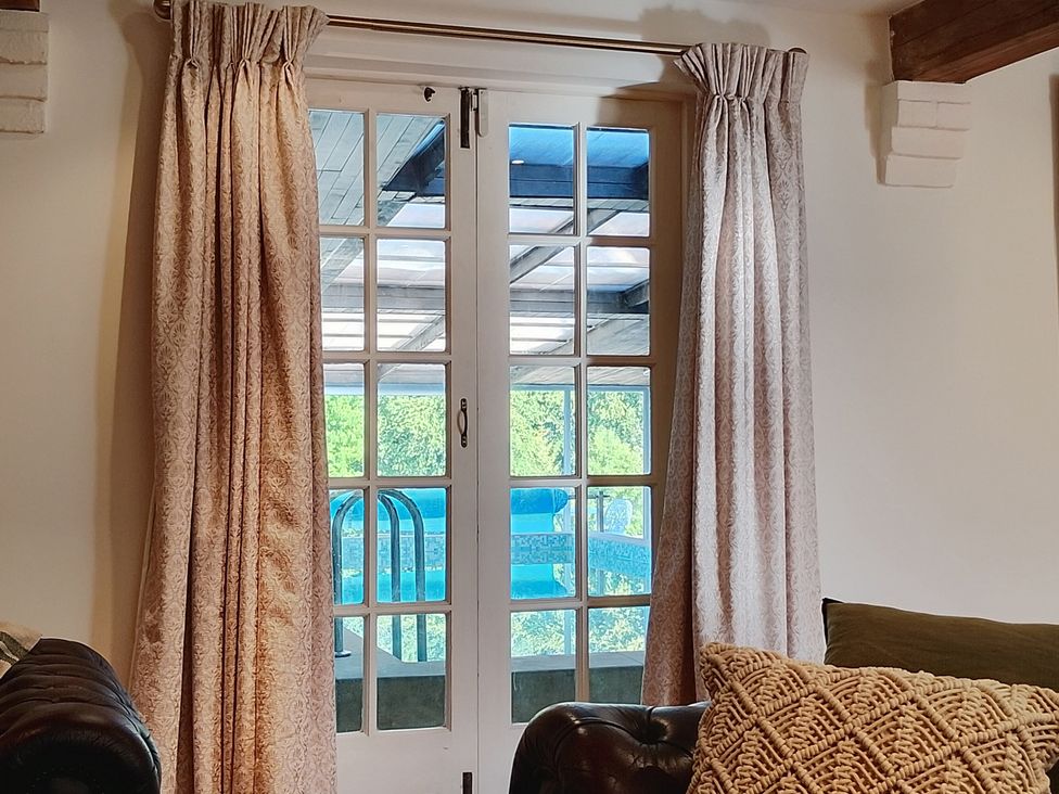 A living room with a glass door leading to a pool at Sharvels Oast House - Pool, Tennis, Luxury Home, Peasmarsh