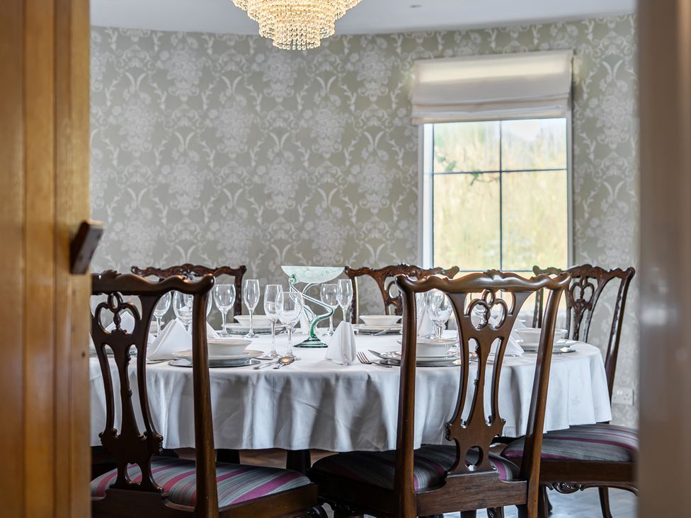 A dining room with a round table set for a meal at Sharvels Oast House - Pool, Tennis, Luxury Home, Peasmarsh