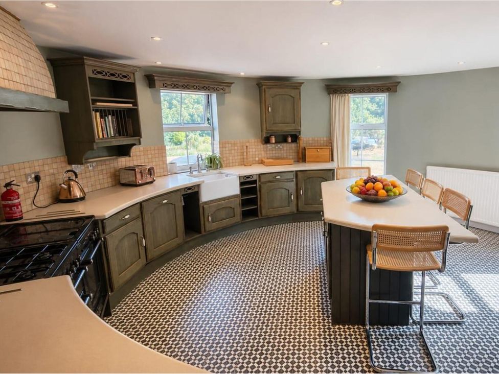 A kitchen with a curved countertop and fruit bowl at Sharvels Oast House - Pool, Tennis, Luxury Home in Peasmarsh