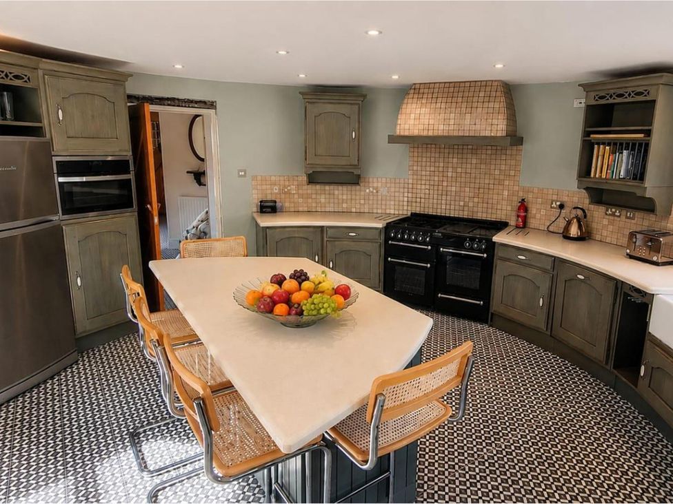 A kitchen with a kitchen island and fruit bowl at Sharvels Oast House - Pool, Tennis, Luxury Home, Peasmarsh