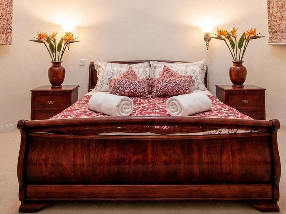 A bedroom with a wooden bed and bedside tables at Sharvels Oast House - Pool, Tennis, Luxury Home, Peasmarsh