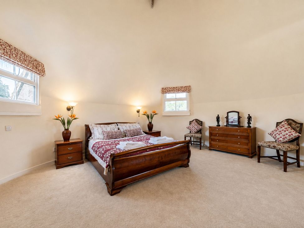 A bedroom with a bed and nightstand at Sharvels Oast House - Pool, Tennis, Luxury Home in Peasmarsh