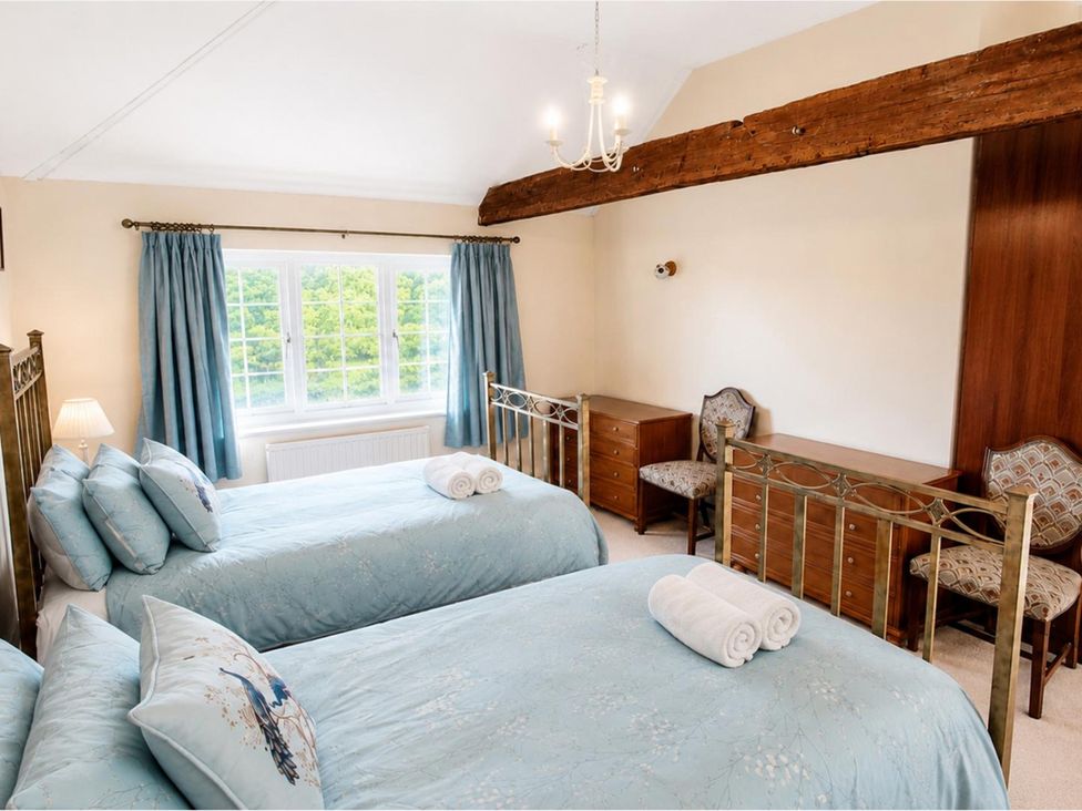 A bedroom with two beds and a window at Sharvels Oast House - Pool, Tennis, Luxury Home Peasmarsh