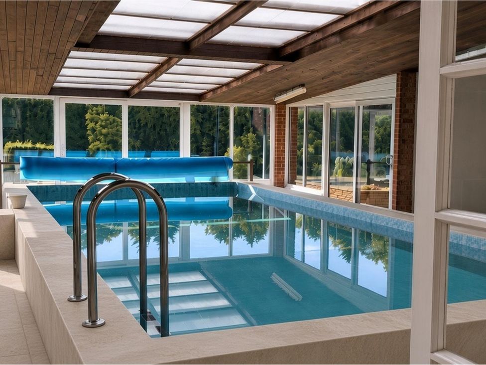An indoor pool area with a swimming pool and a sofa at Sharvels Oast House - Pool, Tennis, Luxury Home in Peasmarsh