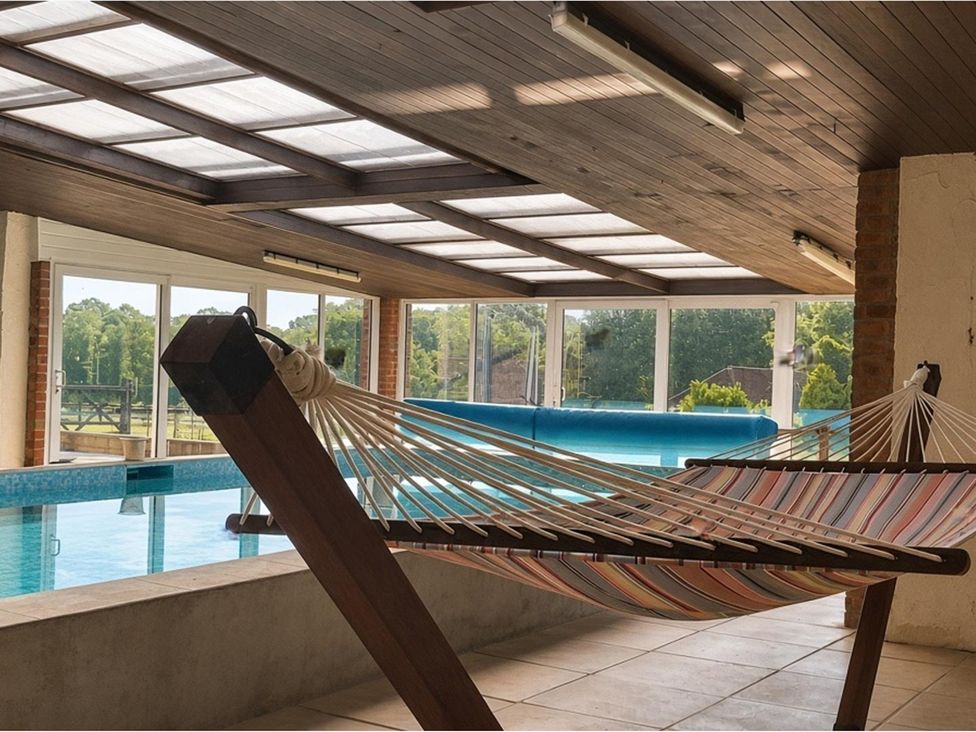An indoor pool area featuring a hammock and swimming pool at Sharvels Oast House - Pool, Tennis, Luxury Home, Peasmarsh