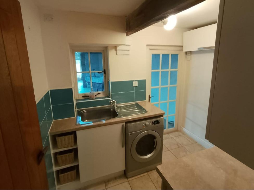 A laundry room with a washing machine and sink at Sharvels Oast House - Pool, Tennis, Luxury Home, Peasmarsh