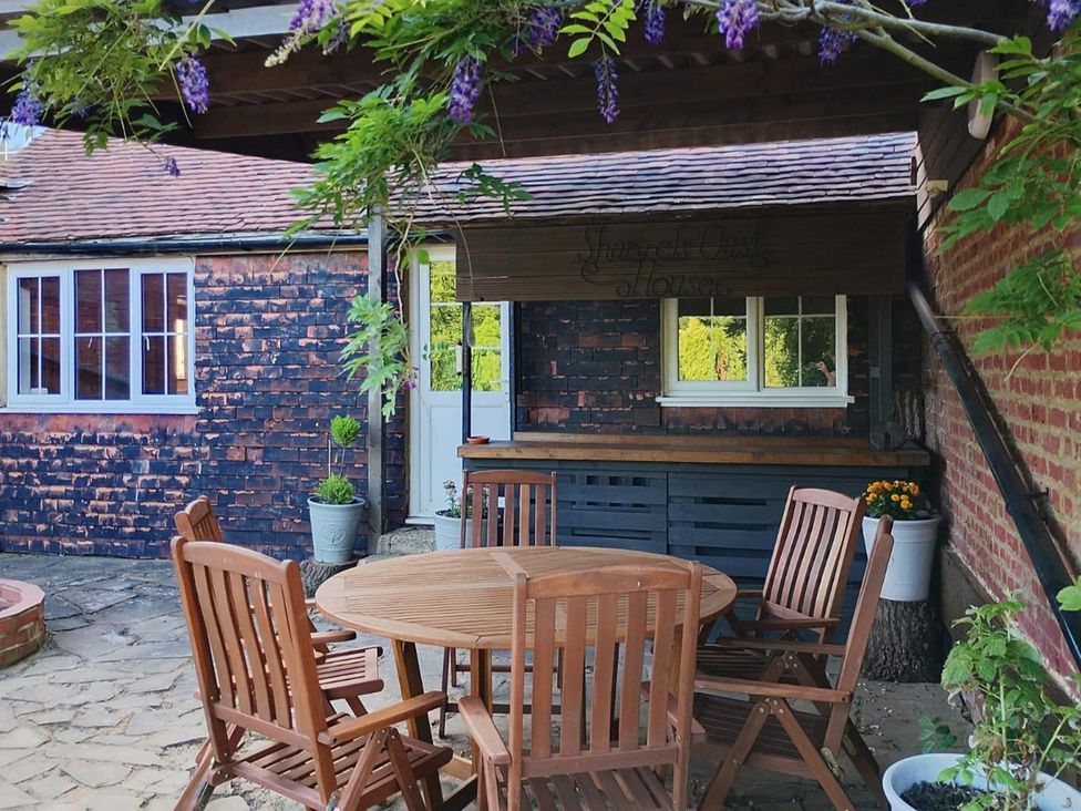 A patio with table and chairs at Sharvels Oast House - Pool, Tennis, Luxury Home Peasmarsh