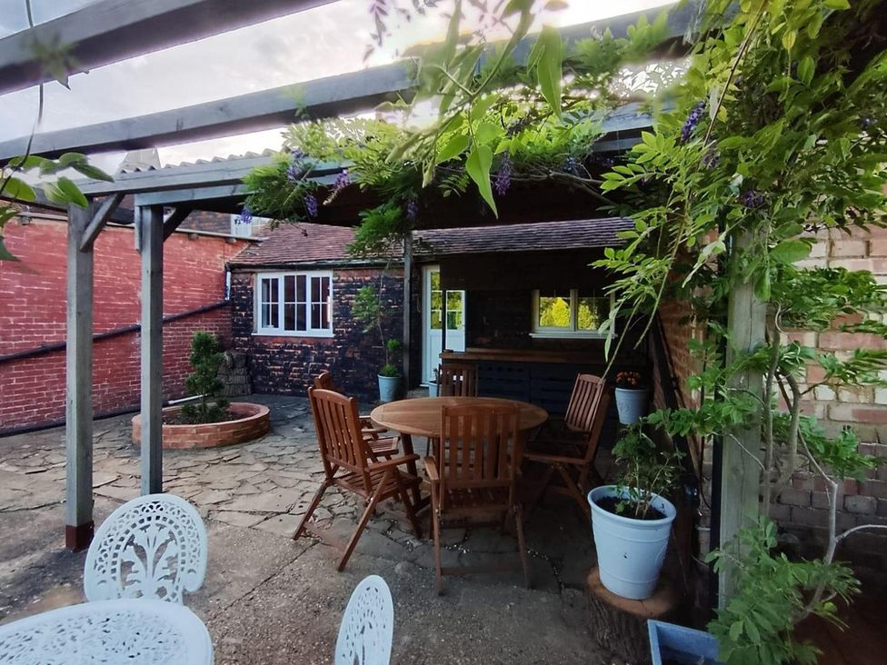A garden area with a table and chairs at Sharvels Oast House - Pool, Tennis, Luxury Home, Peasmarsh