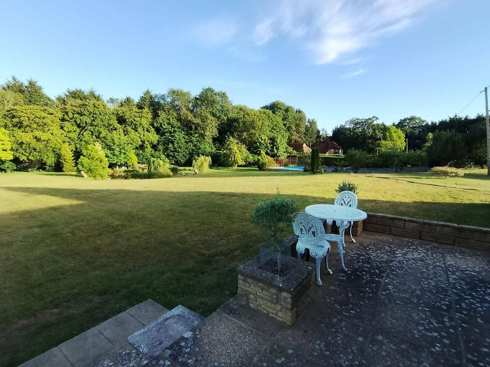 A garden with a table and chairs at Sharvels Oast House - Pool, Tennis, Luxury Home in Peasmarsh