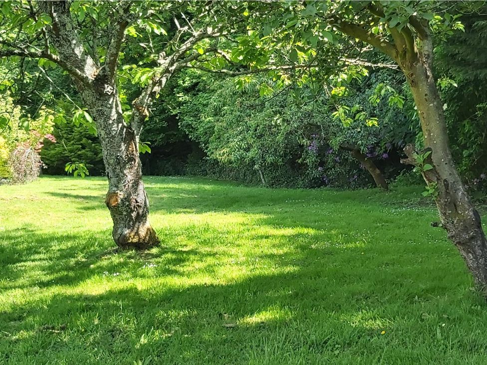 A garden with trees and grass at Sharvels Oast House - Pool, Tennis, Luxury Home, Peasmarsh