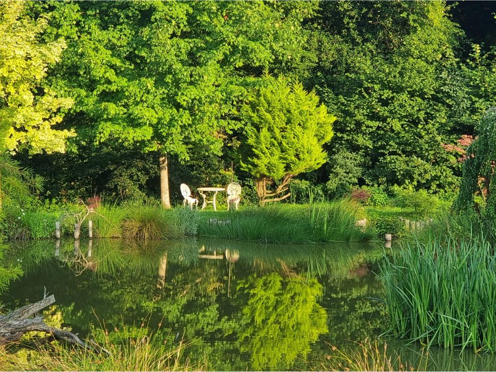 A garden with a pond and a table with chairs at Sharvels Oast House - Pool, Tennis, Luxury Home, Peasmarsh