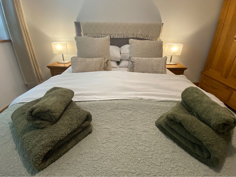 A bedroom with a bed, pillows, towels and a wardrobe at Quiet, Modern Ground Floor Annex Near Theatr Clwyd, Sychdyn