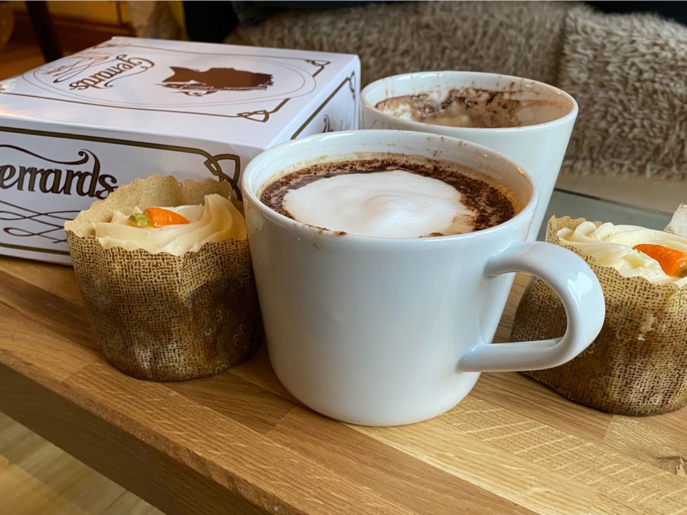 A cup of hot chocolate with cakes and a box at Quiet, Modern Ground Floor Annex Near Theatr Clwyd, Sychdyn