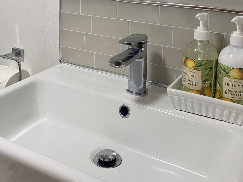 A bathroom sink with a faucet and two soap dispensers at Quiet, Modern Ground Floor Annex Near Theatr Clwyd in Sychdyn