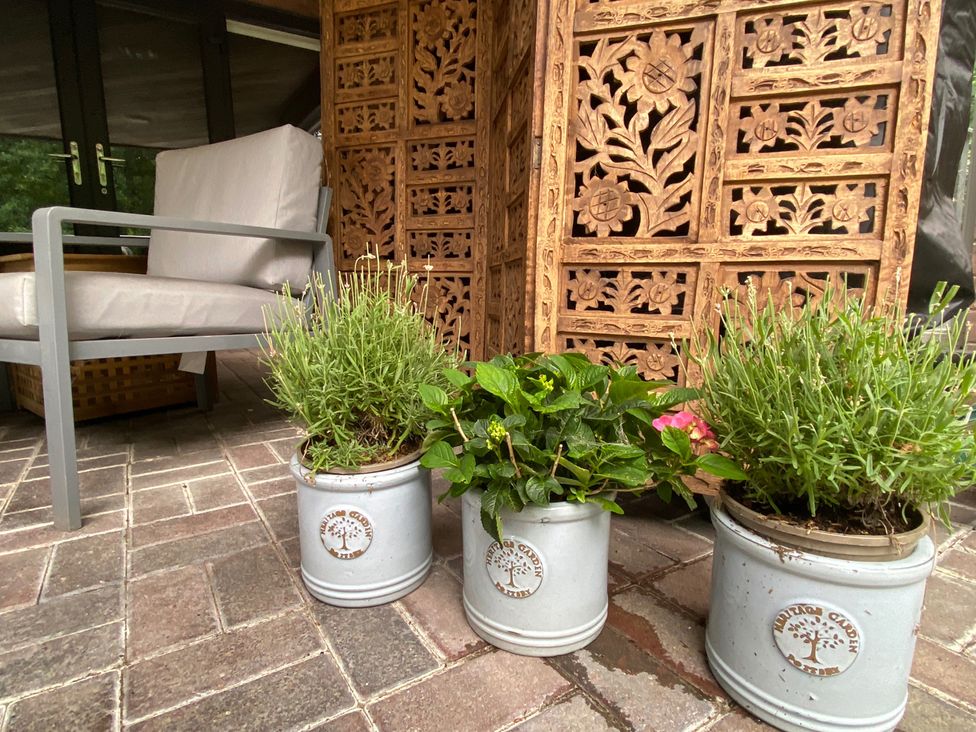 An outdoor seating area with plants and a decorative screen at Quiet, Modern Ground Floor Annex Near Theatr Clwyd, Sychdyn
