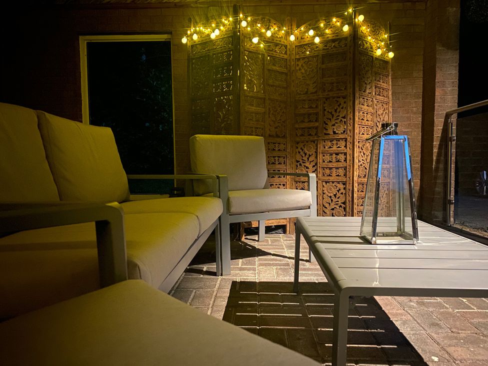 An outdoor sitting area with a sofa and lantern at Quiet, Modern Ground Floor Annex Near Theatr Clwyd, Sychdyn