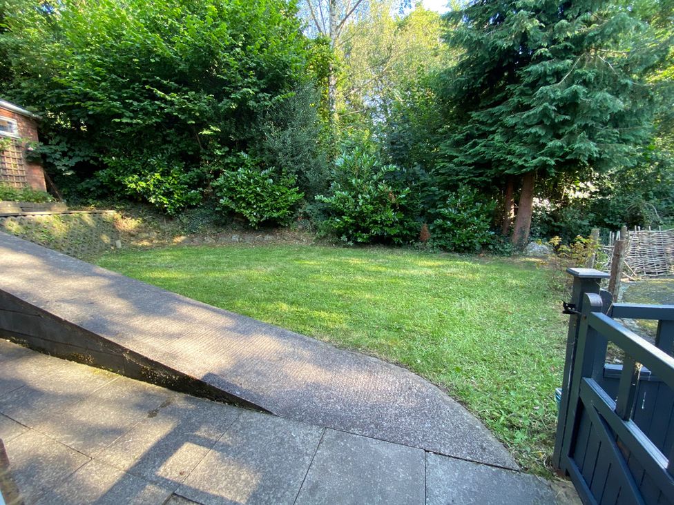 A garden area with grass and surrounding trees at Quiet, Modern Ground Floor Annex Near Theatr Clwyd in Sychdyn