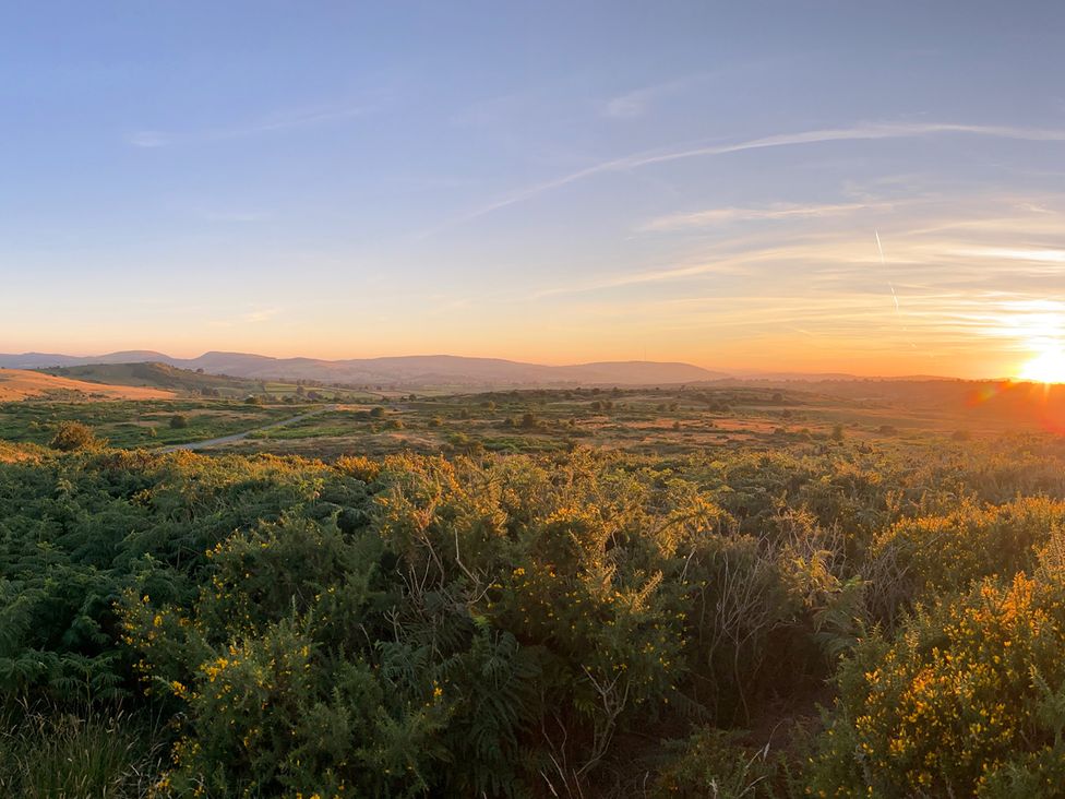 A scenic view of hills and valley at sunset in Sychdyn