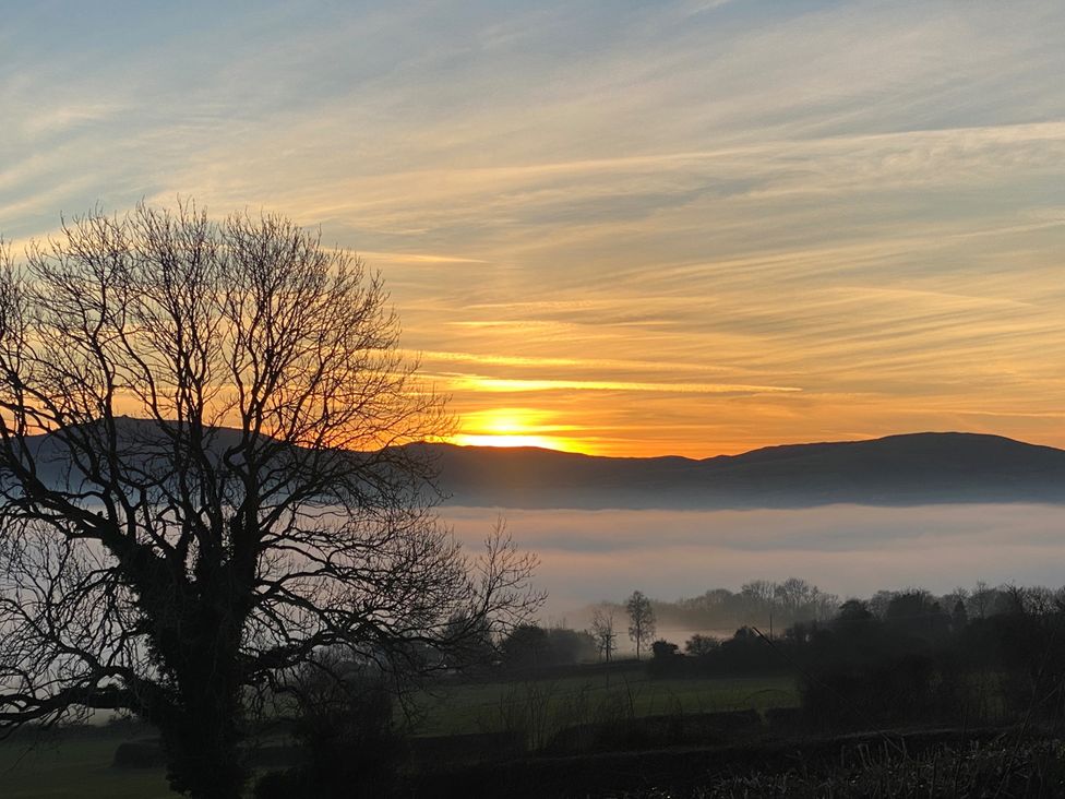 A sunset over foggy mountains and trees at Quiet, Modern Ground Floor Annex Near Theatr Clwyd, Sychdyn