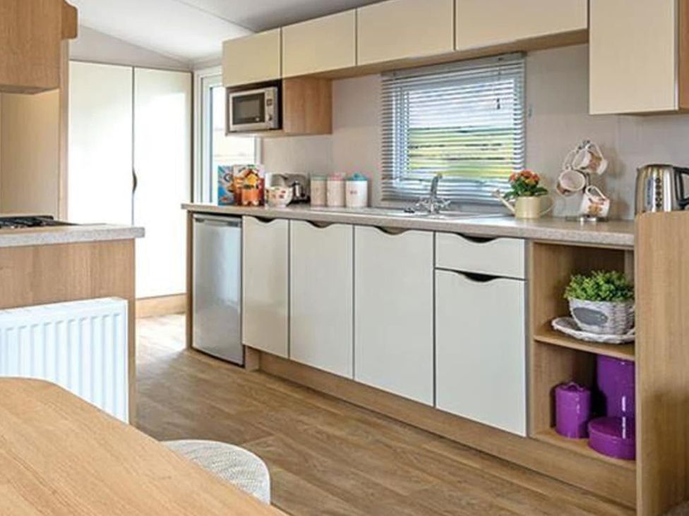A kitchen with cabinets and appliances at Seafront Caravan - Golden Sands - 6 Berth by Your Away Stays Kinmel Bay