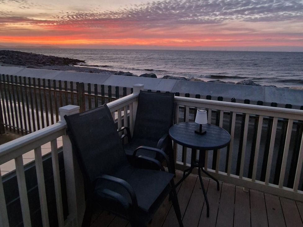 A patio with chairs and a table overlooking the ocean at Seafront Caravan - Golden Sands - 6 Berth by Your Away Stays in Kinmel Bay