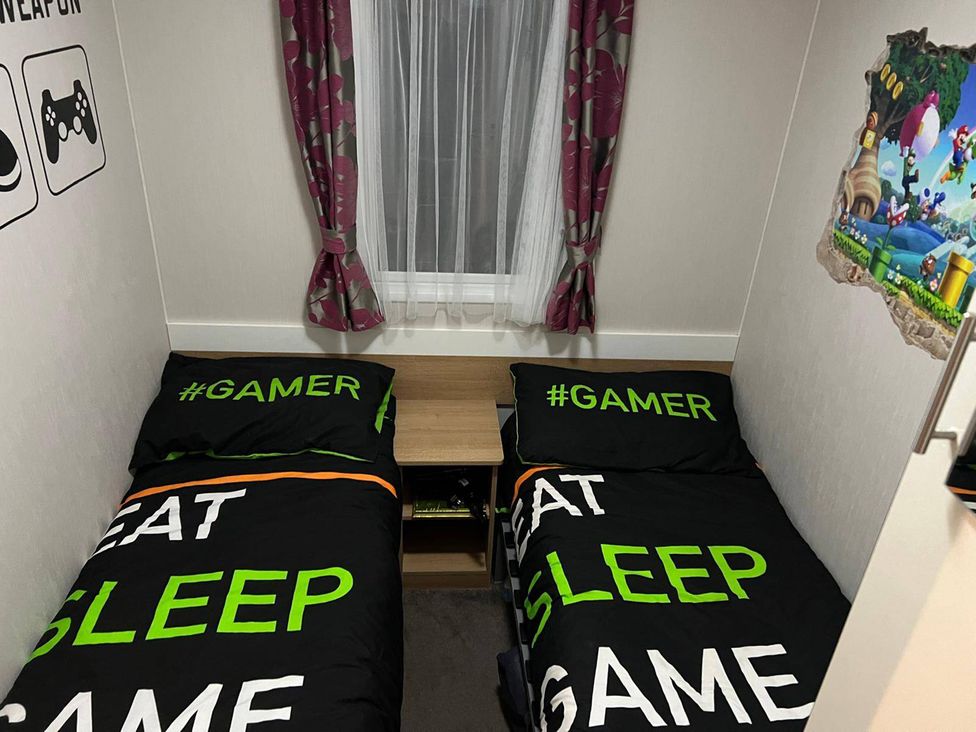 A bedroom with two beds featuring gaming-themed bedding at Seafront Caravan - Golden Sands - 6 Berth by Your Away Stays, Kinmel Bay