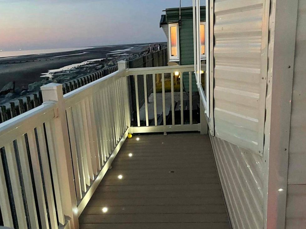 An outdoor area with a balcony and view of the beach at Seafront Caravan - Golden Sands - 6 Berth by Your Away Stays, Kinmel Bay