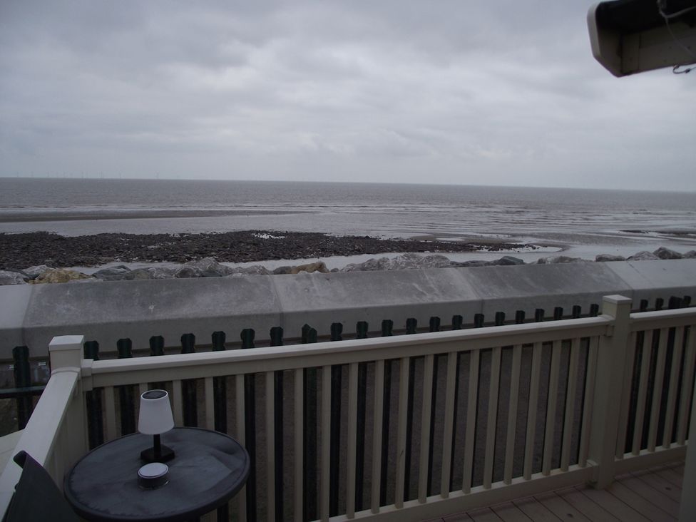A view of the sea and rocks from a deck at Seafront Caravan - Golden Sands - 6 Berth by Your Away Stays in Kinmel Bay