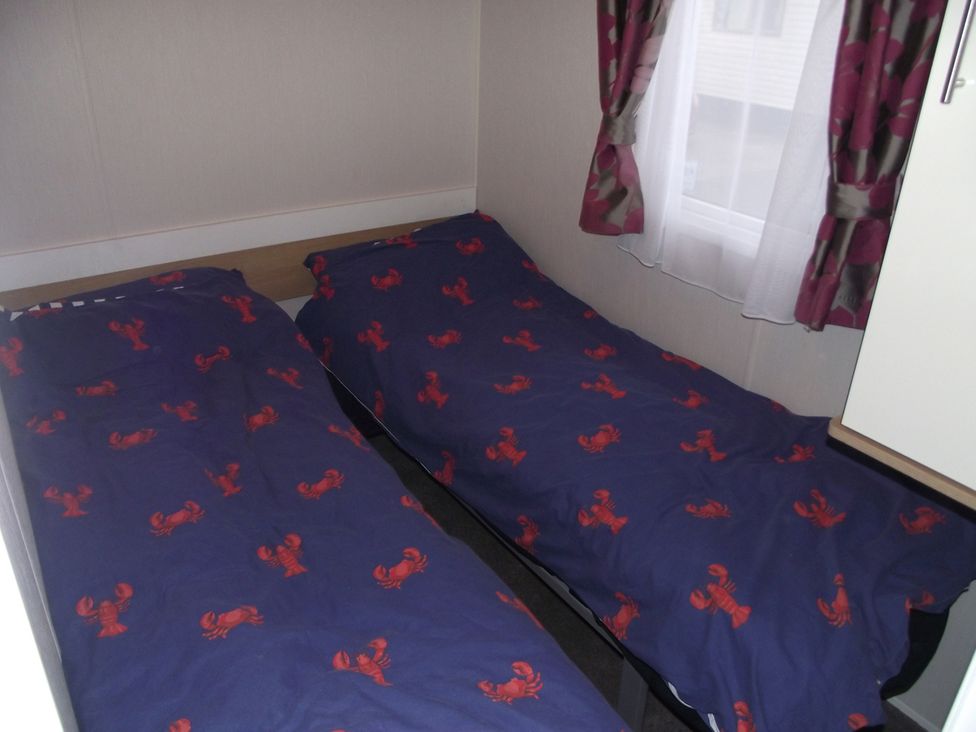 A bedroom with two beds and a window at Seafront Caravan - Golden Sands - 6 Berth by Your Away Stays, Kinmel Bay