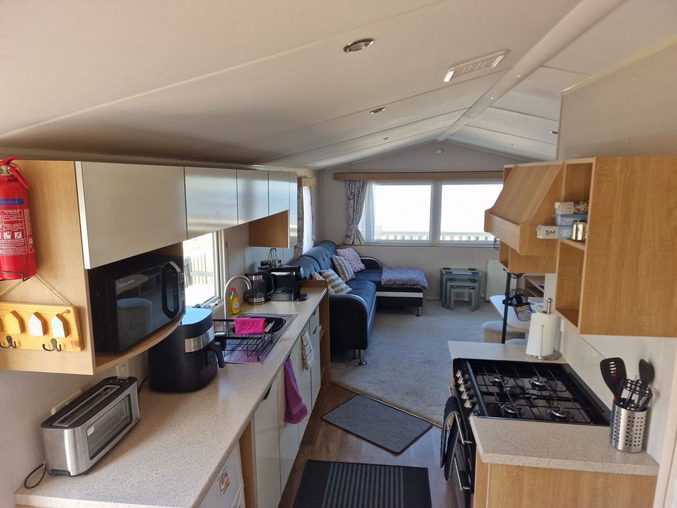 A kitchen with appliances and a couch at Seafront Caravan - Golden Sands - 6 Berth by Your Away Stays, Kinmel Bay