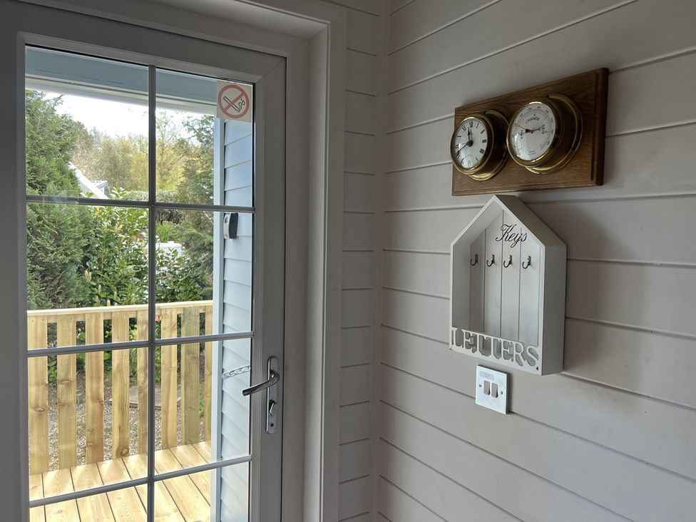An entrance with a clock and key holder at Holly Blue - Cosy wooden lodge, Kippford