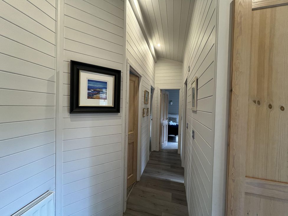 A hallway with wooden door and framed picture at Holly Blue - Cosy wooden lodge, Kippford