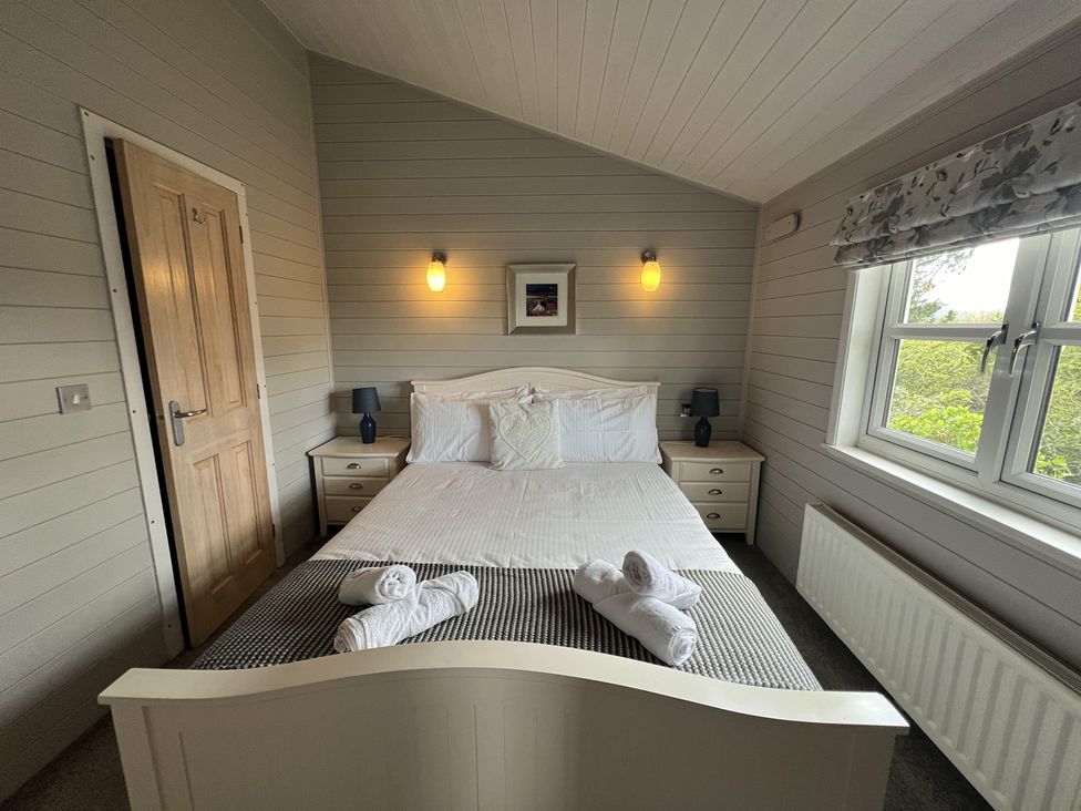 A bedroom with a bed and bedside tables at Holly Blue - Cosy wooden lodge, Kippford