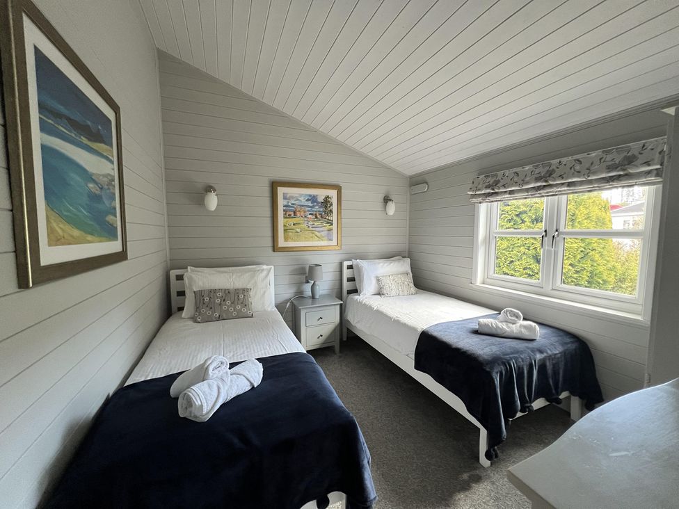A bedroom with two beds and artwork at Holly Blue - Cosy wooden lodge, Kippford