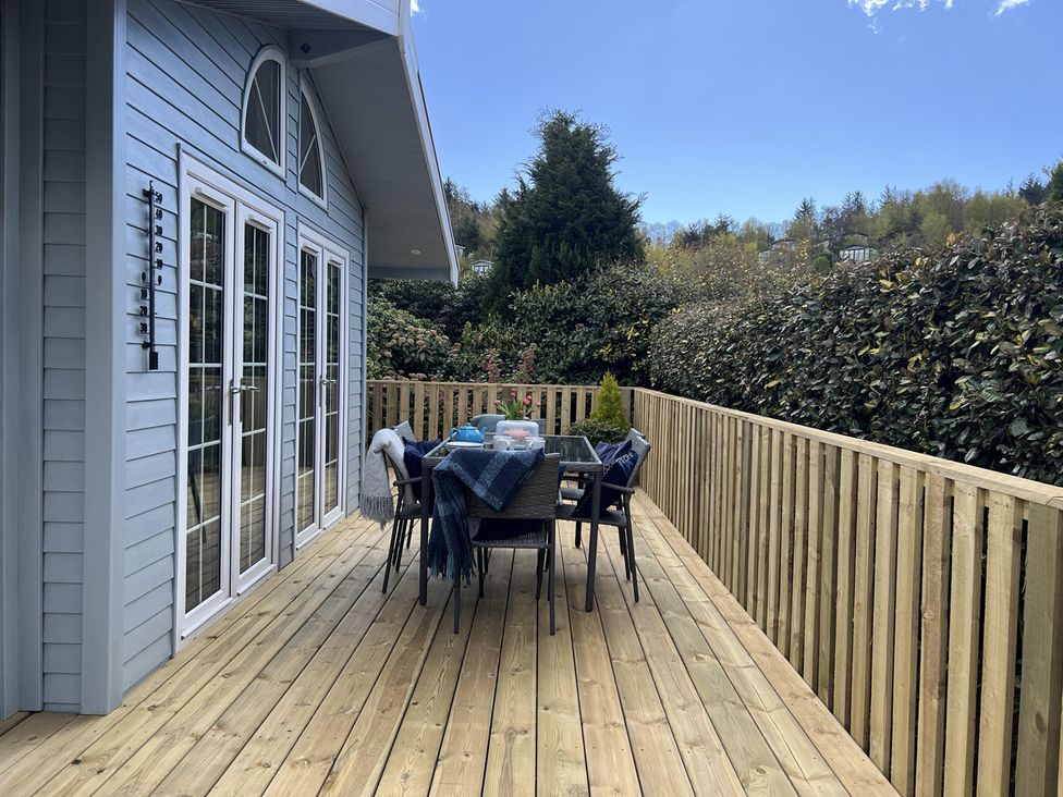 A deck with a table and chairs at Holly Blue - Cosy wooden lodge, Kippford