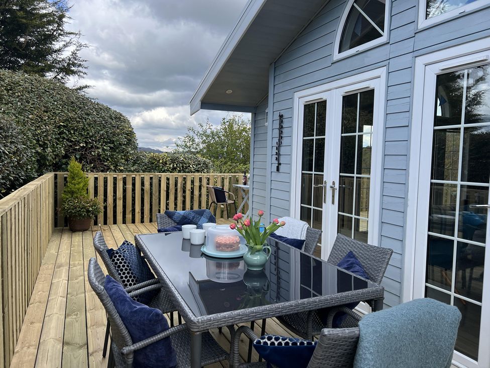 An outdoor dining area with a table and chairs at Holly Blue - Cosy wooden lodge, Kippford