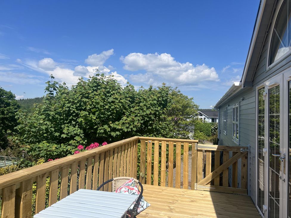 A decking area with a table and chair at Holly Blue - Cosy wooden lodge, Kippford