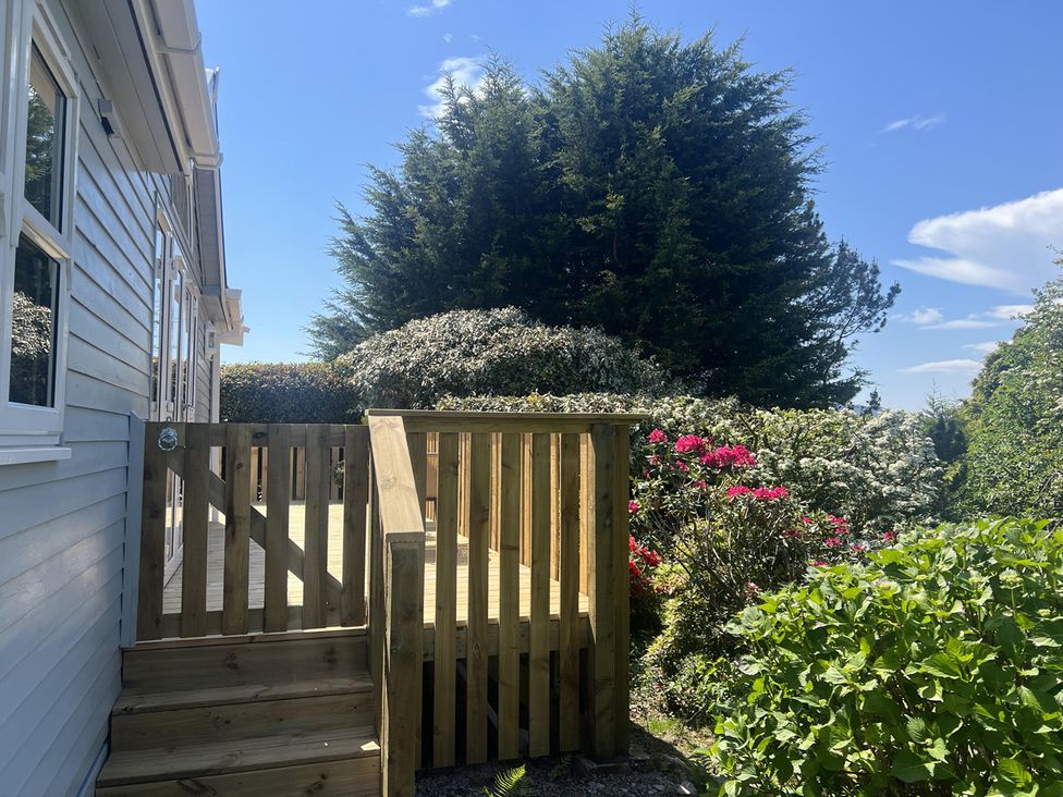 A deck area with stairs and surrounding greenery at Holly Blue - Cosy wooden lodge, Kippford