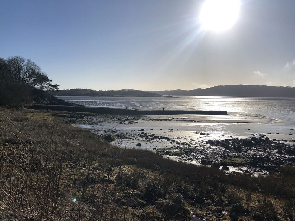 A view of the shoreline with rocks and water at Holly Blue - Cosy wooden lodge, Kippford
