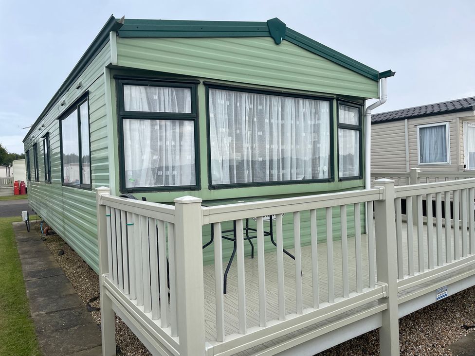 A static caravan with decking and a table in an outdoor area at 4 Bed Lodge Sleeps 8 - Pets & WiFi Free Parking in Ingoldmells