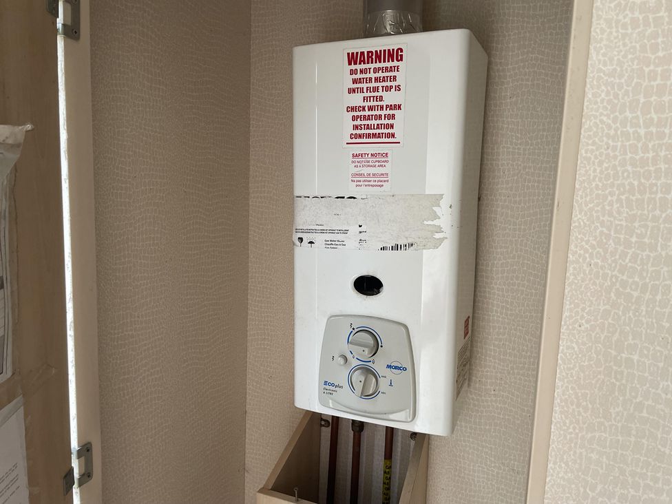 A water heater and warning notice in a utility room at 4 Bed Lodge Sleeps 8 - Pets & WiFi Free Parking in Ingoldmells