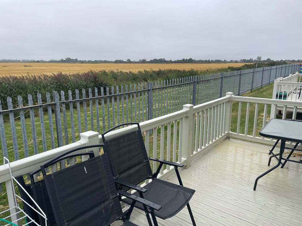 An outdoor area with chairs and a table overlooking a grassy field at 4 Bed Lodge Sleeps 8 - Pets & WiFi Free Parking in Ingoldmells